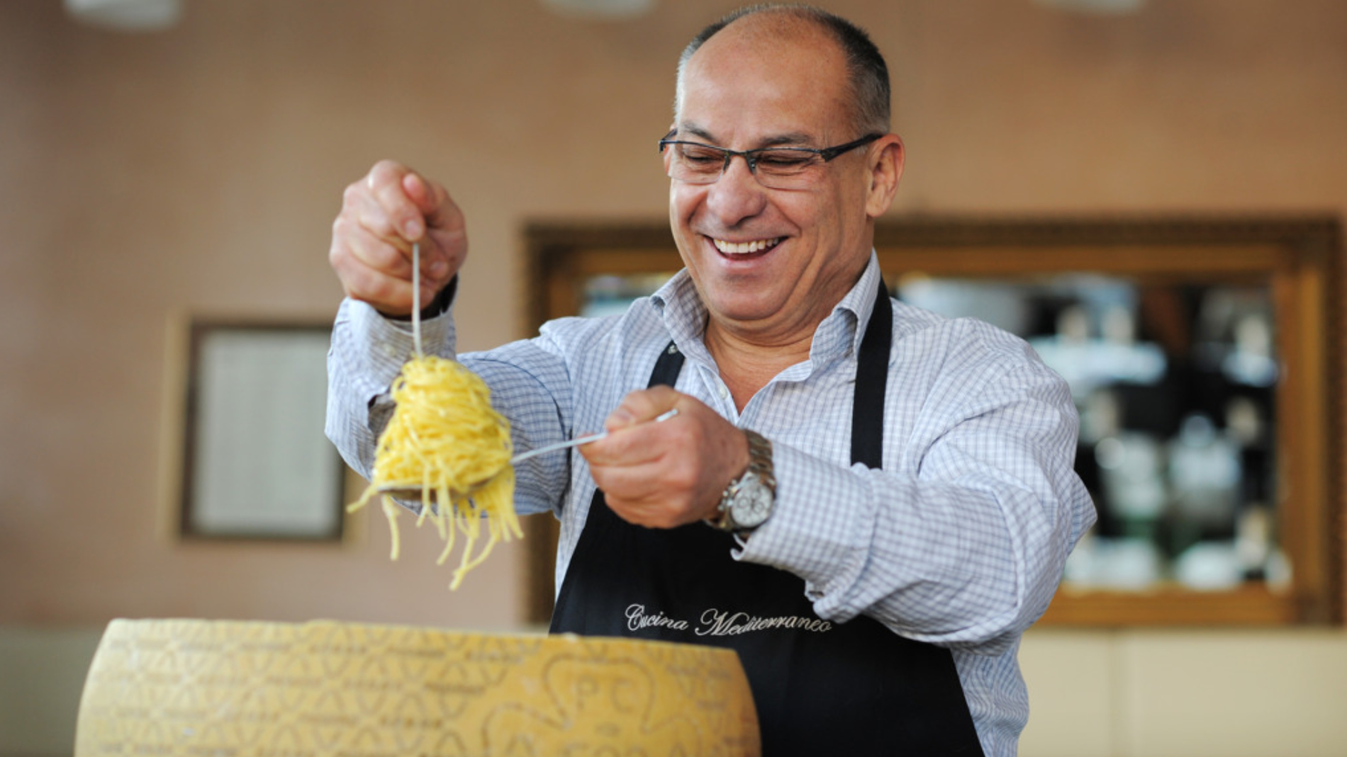 Waiter prepares noodles from a cheese loaf